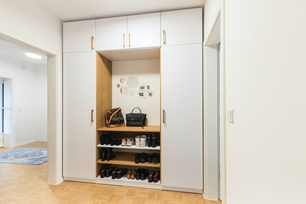 a white closet with a shoe rack and a handbag