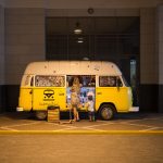 woman and child standing in front of yellow bus in car park